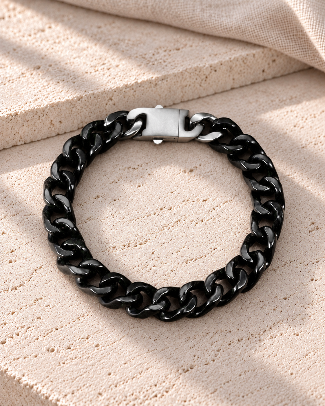 Single Piece Carved Cuban Chain Bracelet in Black Jade, product view on pale limestone.