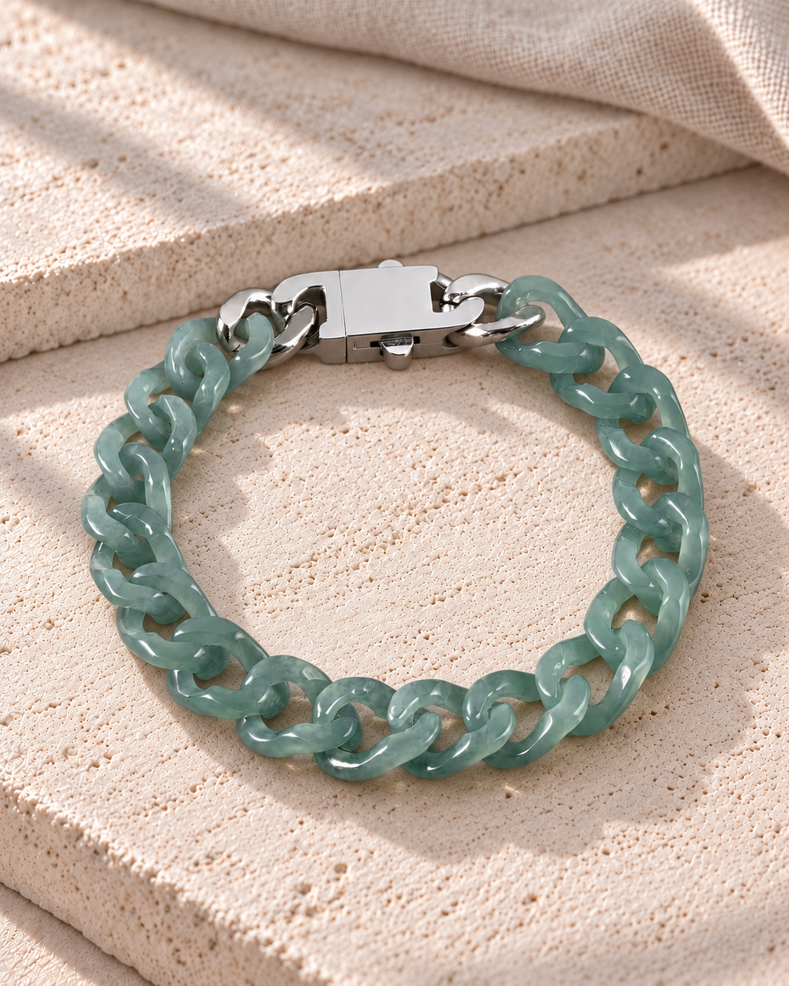 Single Piece Carved Cuban Chain Bracelet in Top Icy Green Jade, product view on pale limestone.