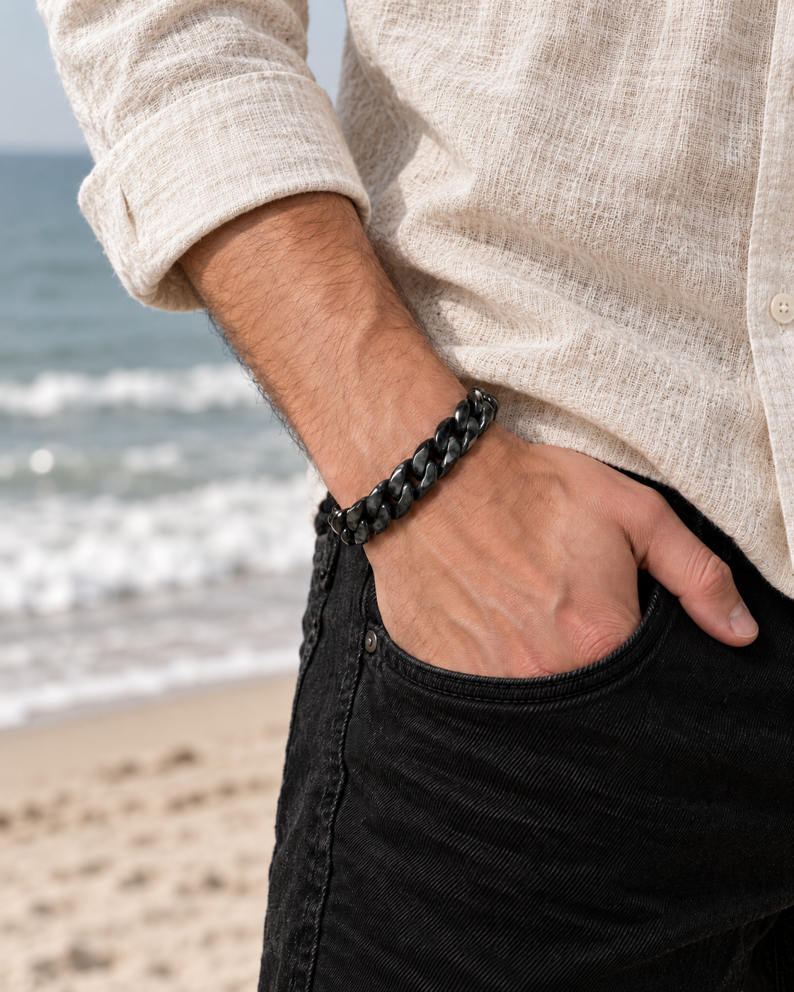 Single Piece Carved Cuban Chain Bracelet in Black Jade, worn with a hand in a pocket at the beach.