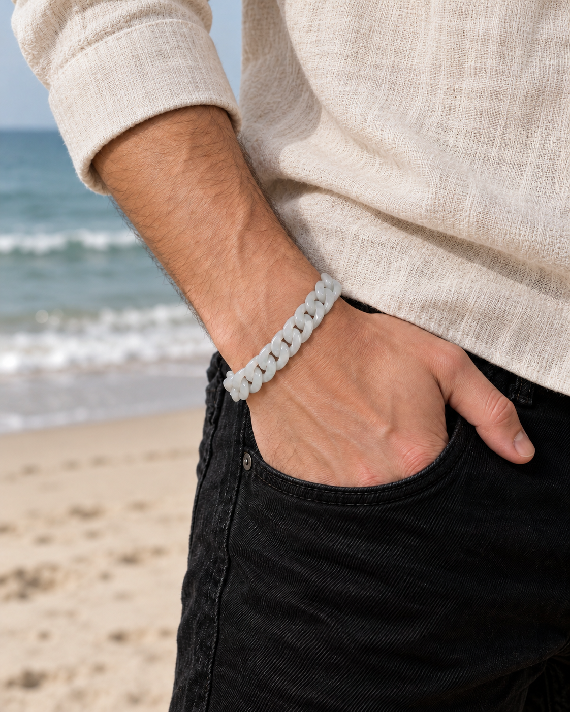 Classic Cuban Link Chain Bracelet in White Jade, worn with a hand in a pocket at the beach.