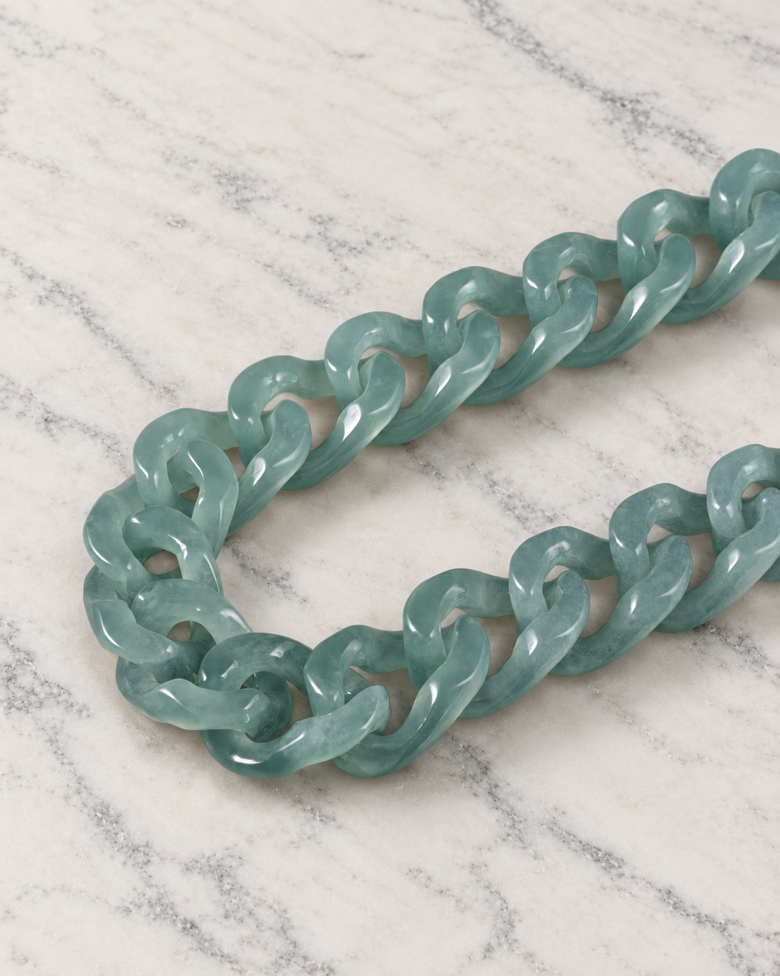Single Piece Carved Cuban Chain Bracelet in Top Icy Green Jade, material and construction close-up on ivory marble.