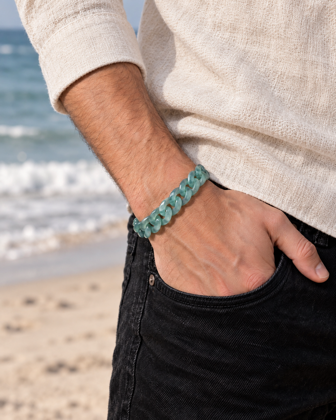Classic Cuban Link Chain Bracelet in Blue-Green Jadeite, worn with a hand in a pocket at the beach.