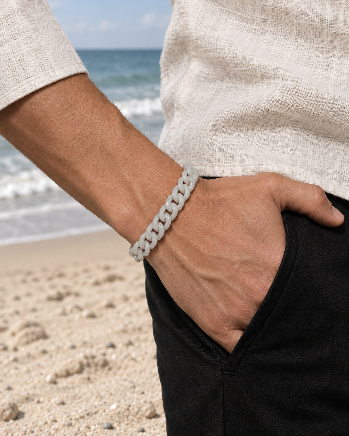 Classic Cuban Link Chain Bracelet in White Jade, worn with a hand in a pocket at the beach.
