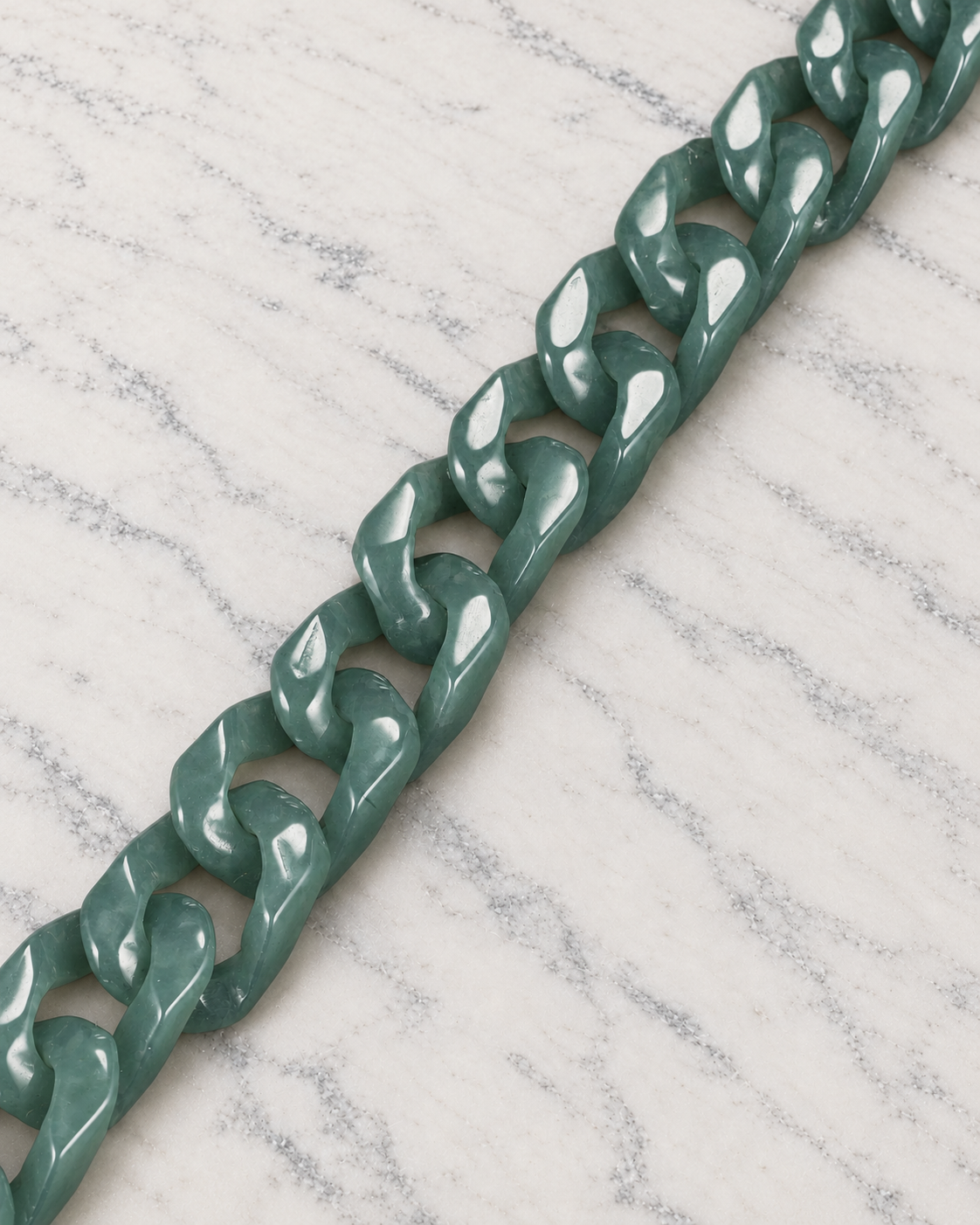 Single Piece Carved Cuban Chain Bracelet in Green Jade, material and construction close-up on ivory marble.