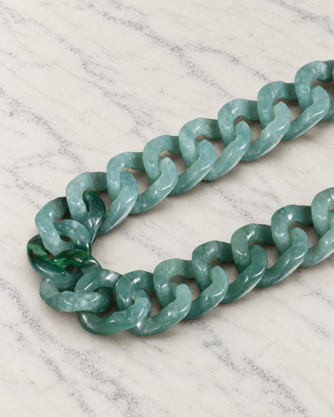 Single Piece Carved Cuban Chain Bracelet in Green Jade, material and construction close-up on ivory marble.