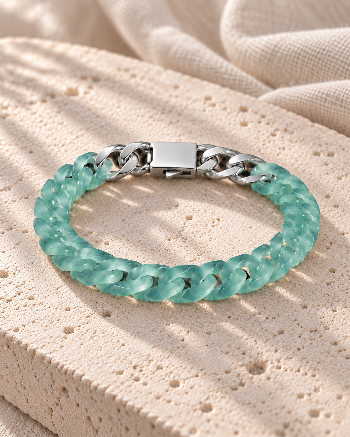 Classic Cuban Link Chain Bracelet In Blue-Green Jadeite on white stone: Rounded limestone block with linen