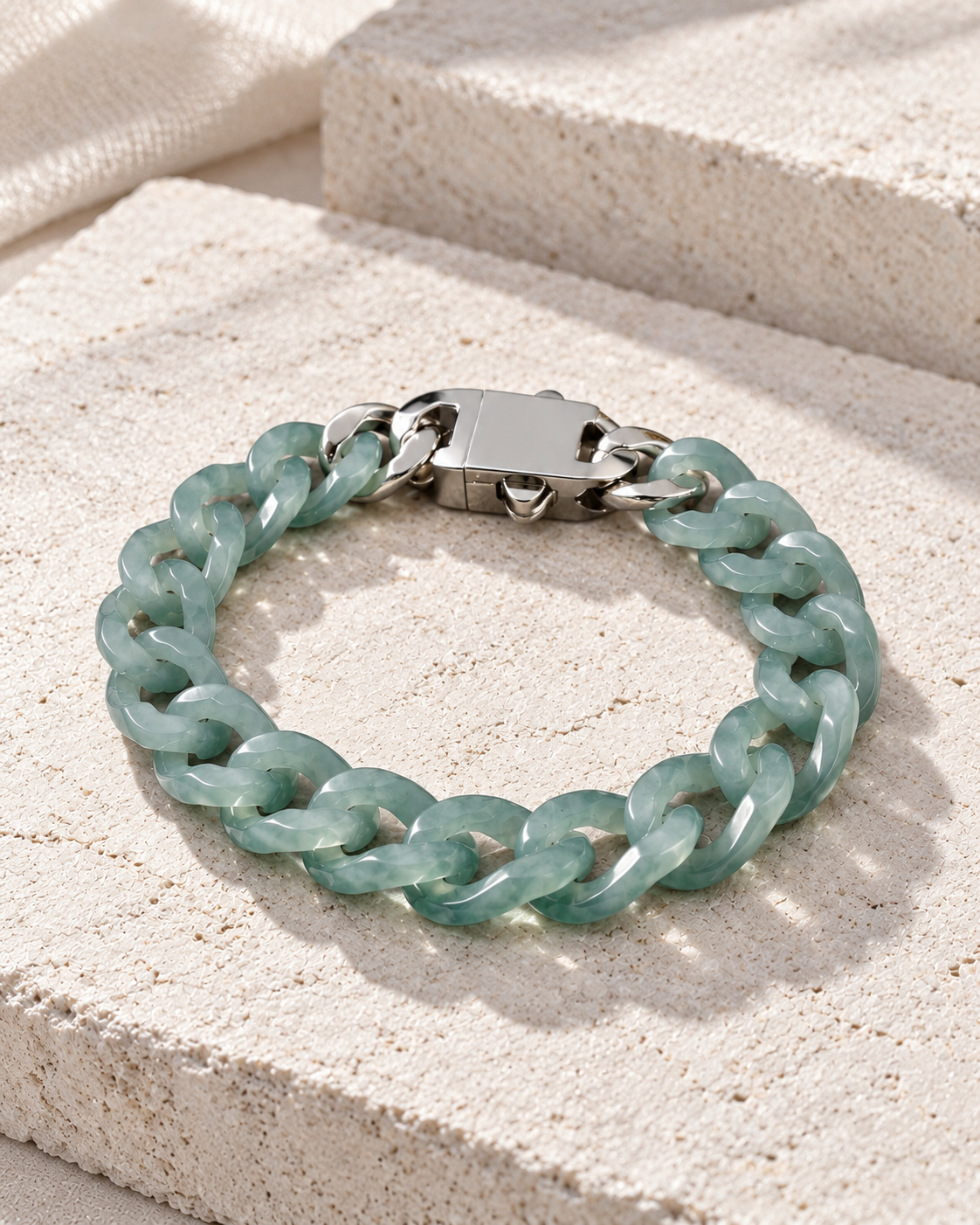Single Piece Carved Cuban Chain Bracelet In Top Icy Green Jade on flat pale stone