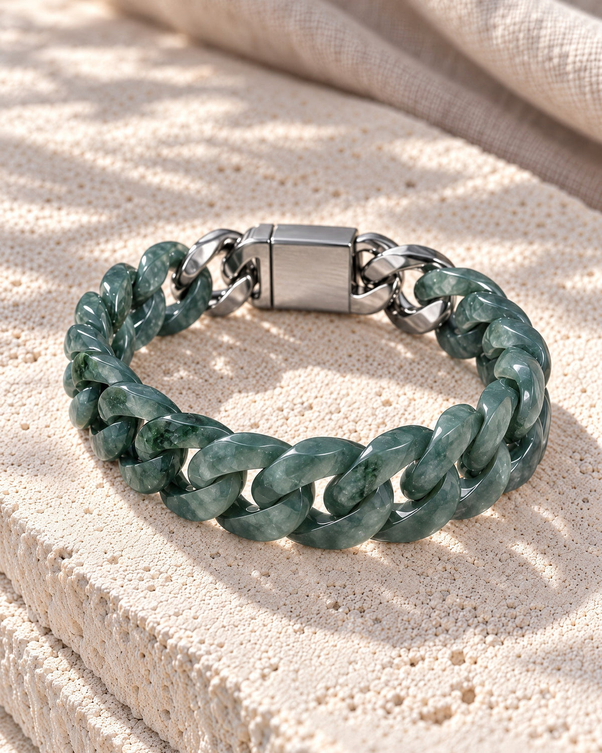 Single Piece Carved Cuban Chain Bracelet In Green Jade on white stone, resting on its side