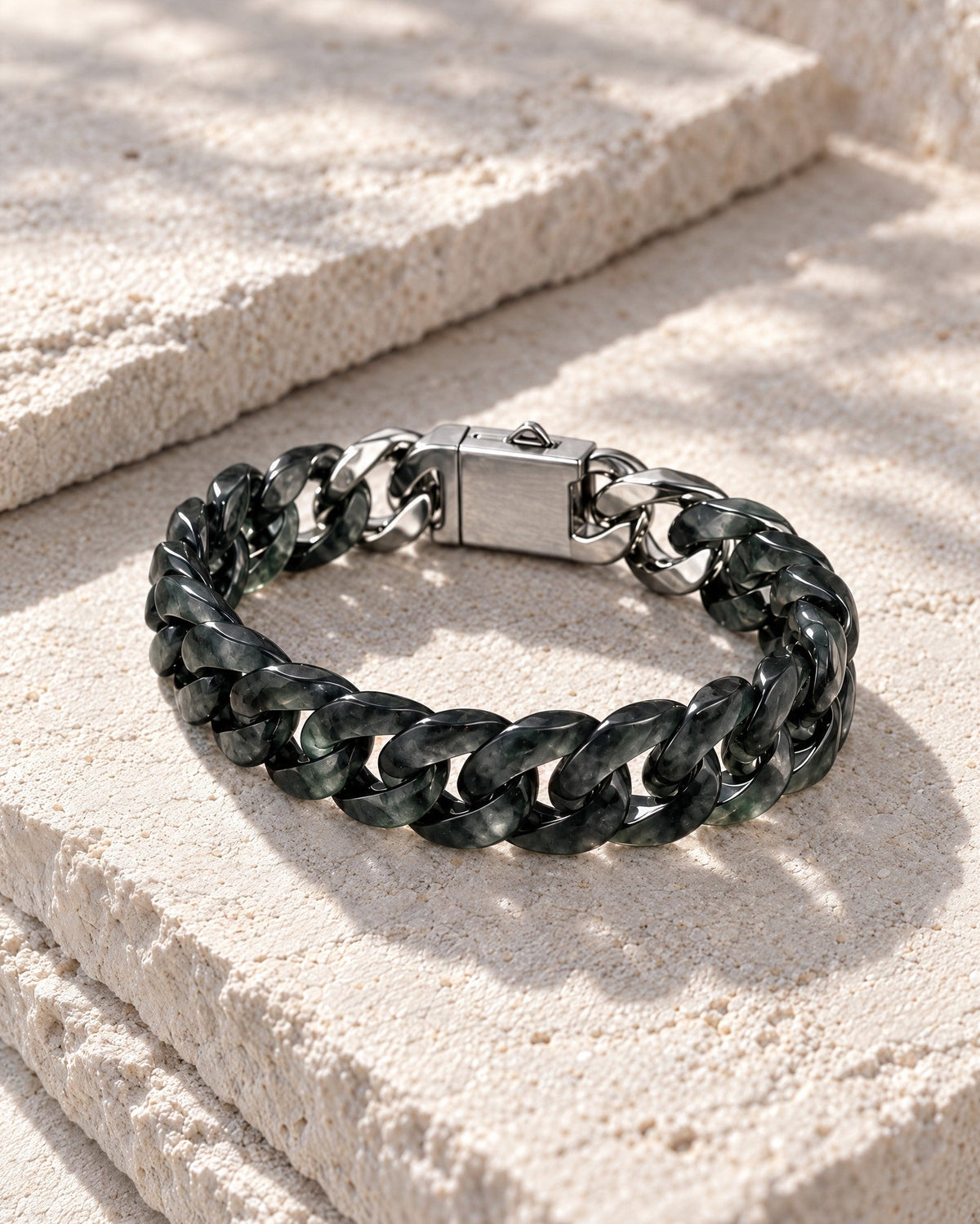 Classic Cuban Link Chain Bracelet In Black Jade resting on its side on pale stone in soft daylight