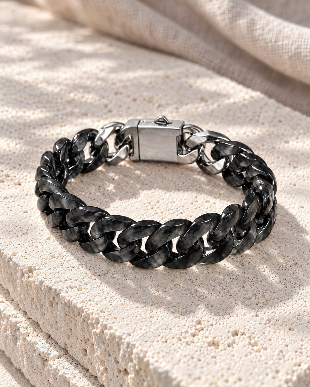 Black Jade carved Cuban bracelet resting on its side on pale stone in soft daylight