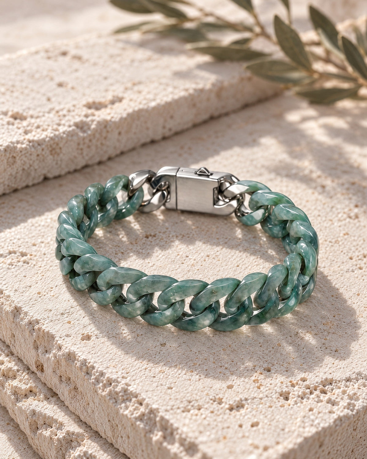Single Piece Carved Cuban Chain Bracelet In Green Jade resting on its side on pale stone in soft daylight