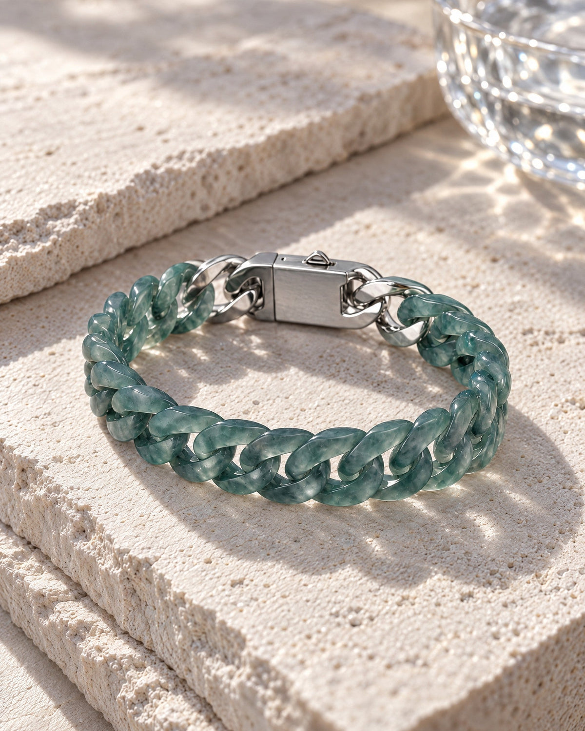 Slim Style Cuban Link Chain Bracelet In Mayan Blue Jade resting on its side on pale stone in soft daylight