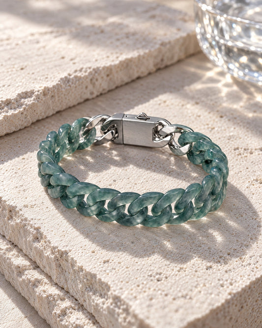 Slim Style Cuban Link Chain Bracelet In Mayan Blue Jade resting on its side on pale stone in soft daylight