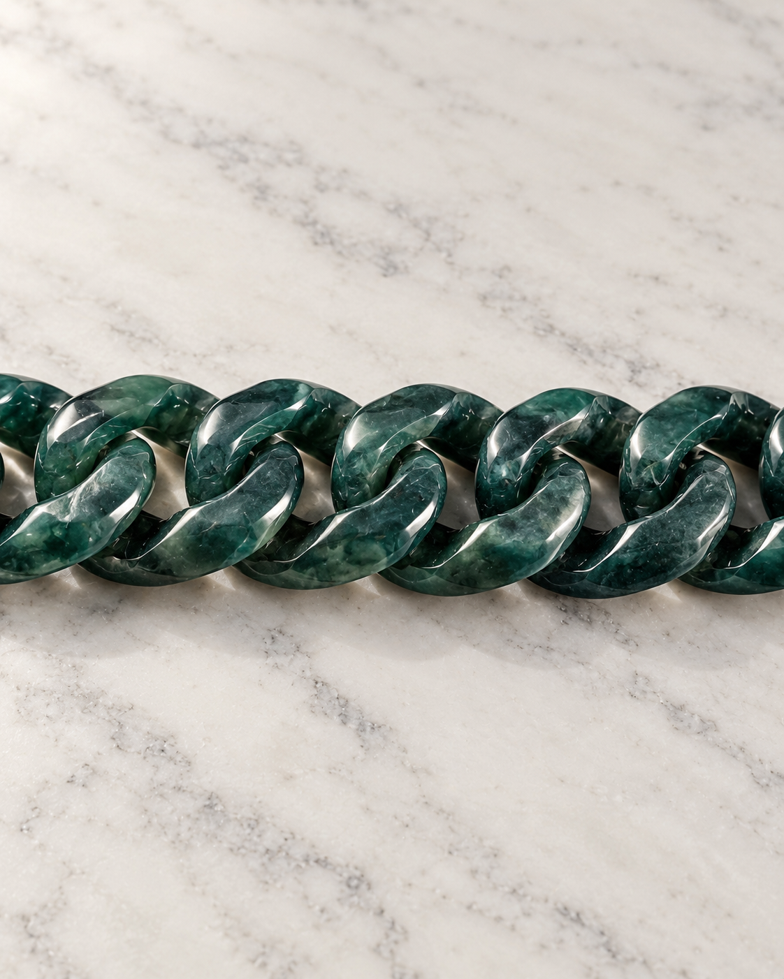 Single Piece Carved Cuban Chain Bracelet In Dark Green Jade on white stone: marble tabletop detail
